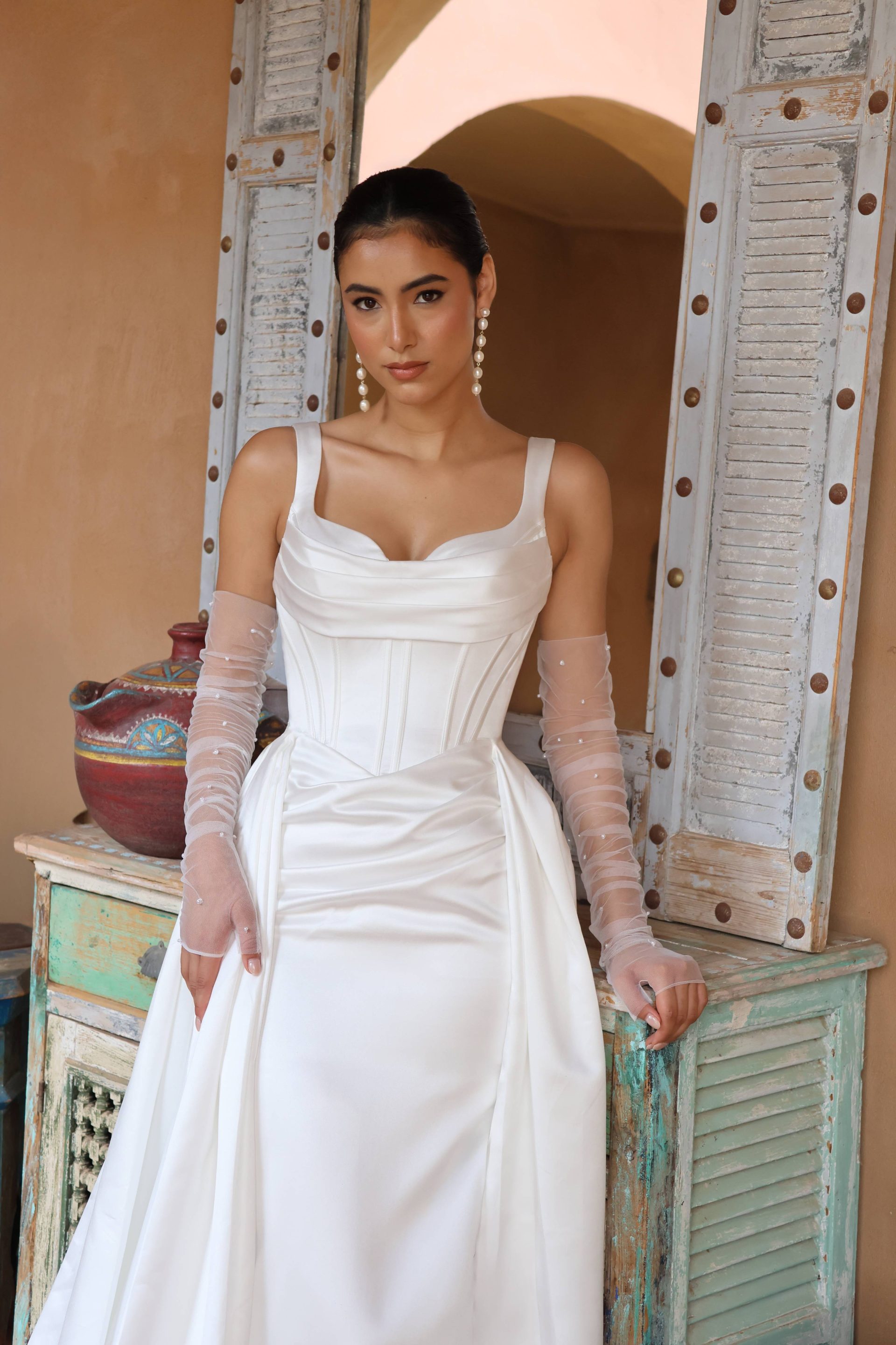 Robe de mariée sirène Sérèna accessoirisée avec des mitaines, style couture minimaliste.