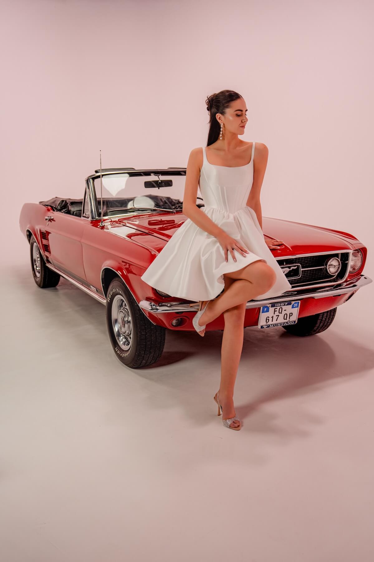la-valerie-robe-mariee-civile-courte-mikado-editorial-toulouse La Valérie, robe de mariée civile courte en mikado dans une voiture vintage rouge, ambiance éditoriale glamour