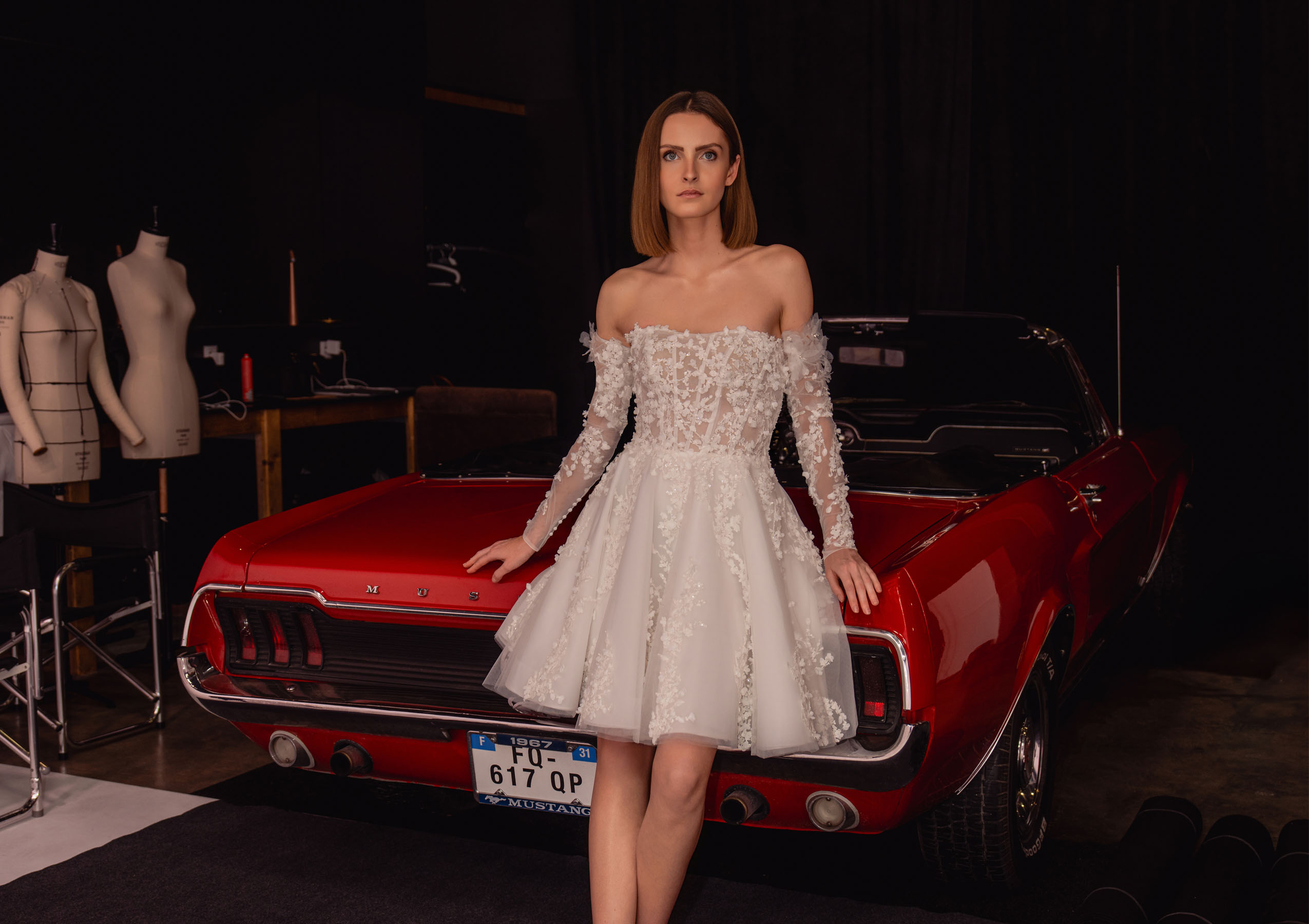 look 7 Monroe, robe de mariée civile courte bustier en dentelle 3D dans un shooting studio avec voiture vintage rouge
