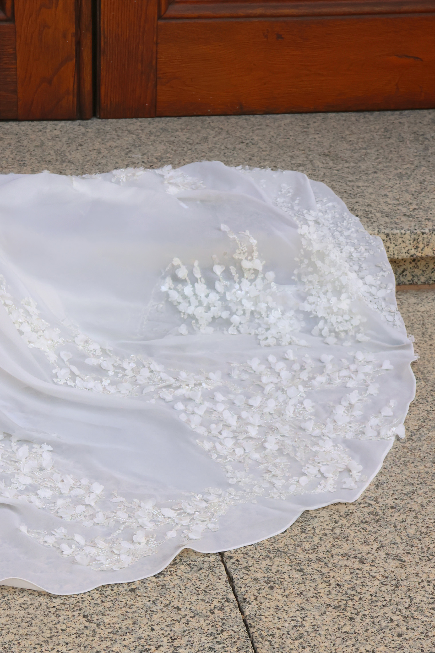 Détail de la traîne en mousseline ornée d’applications de dentelle florale de la robe de mariée Maëlia.