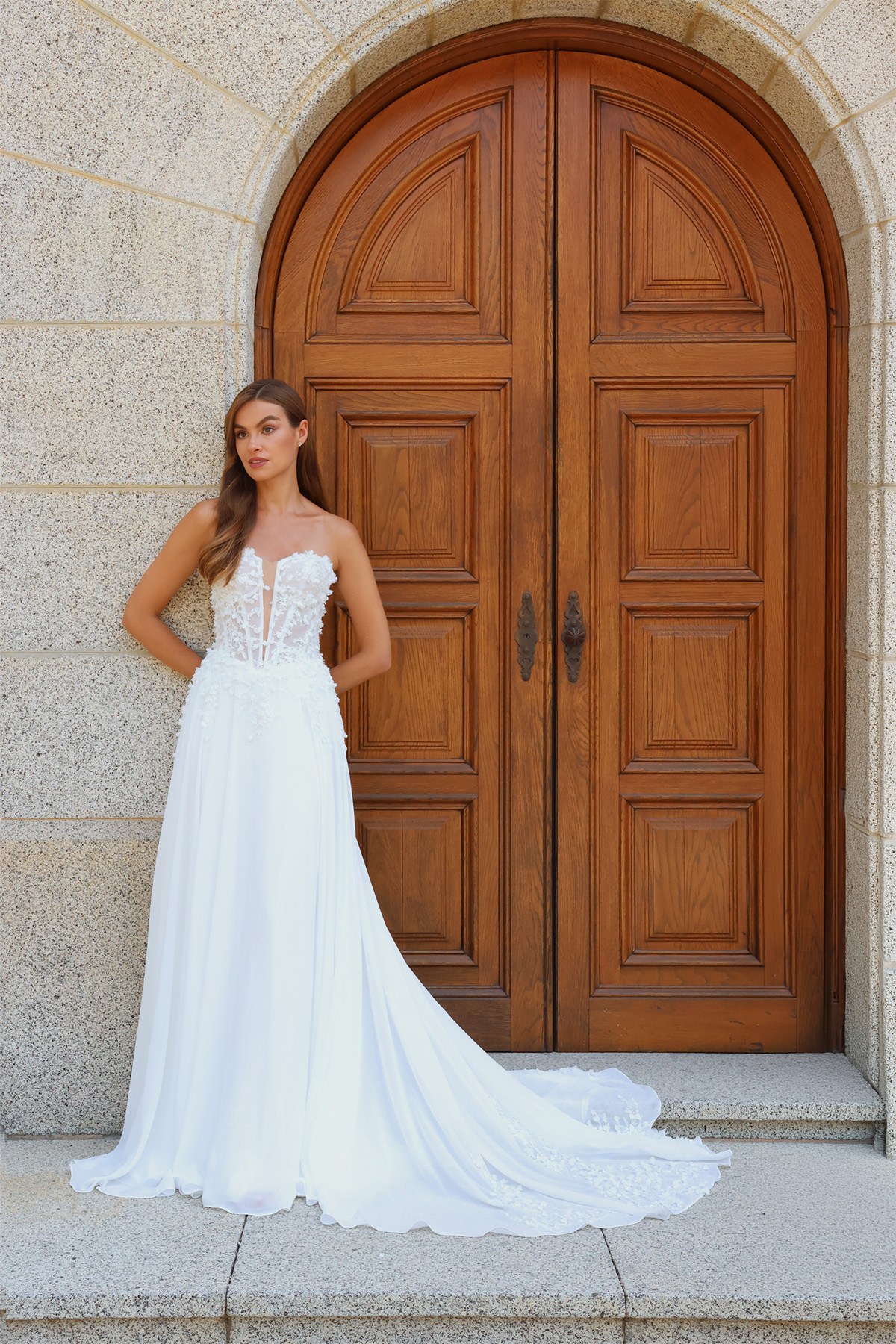 Vue de face de la robe de mariée Maëlia avec bustier transparent en dentelle, jupe fluide en mousseline et longue traîne.