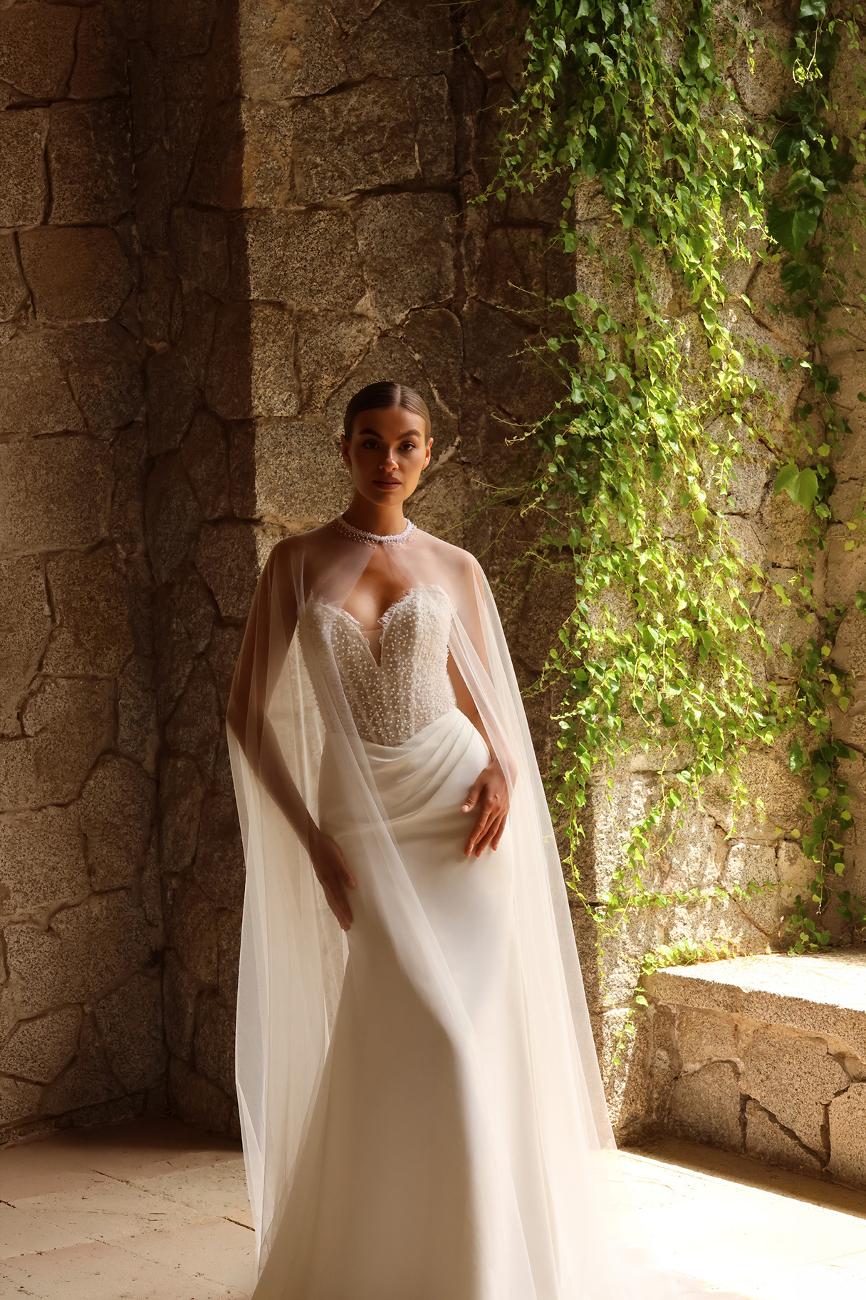 Robe de mariée Amarande avec bustier perlé et cape légère en tulle.