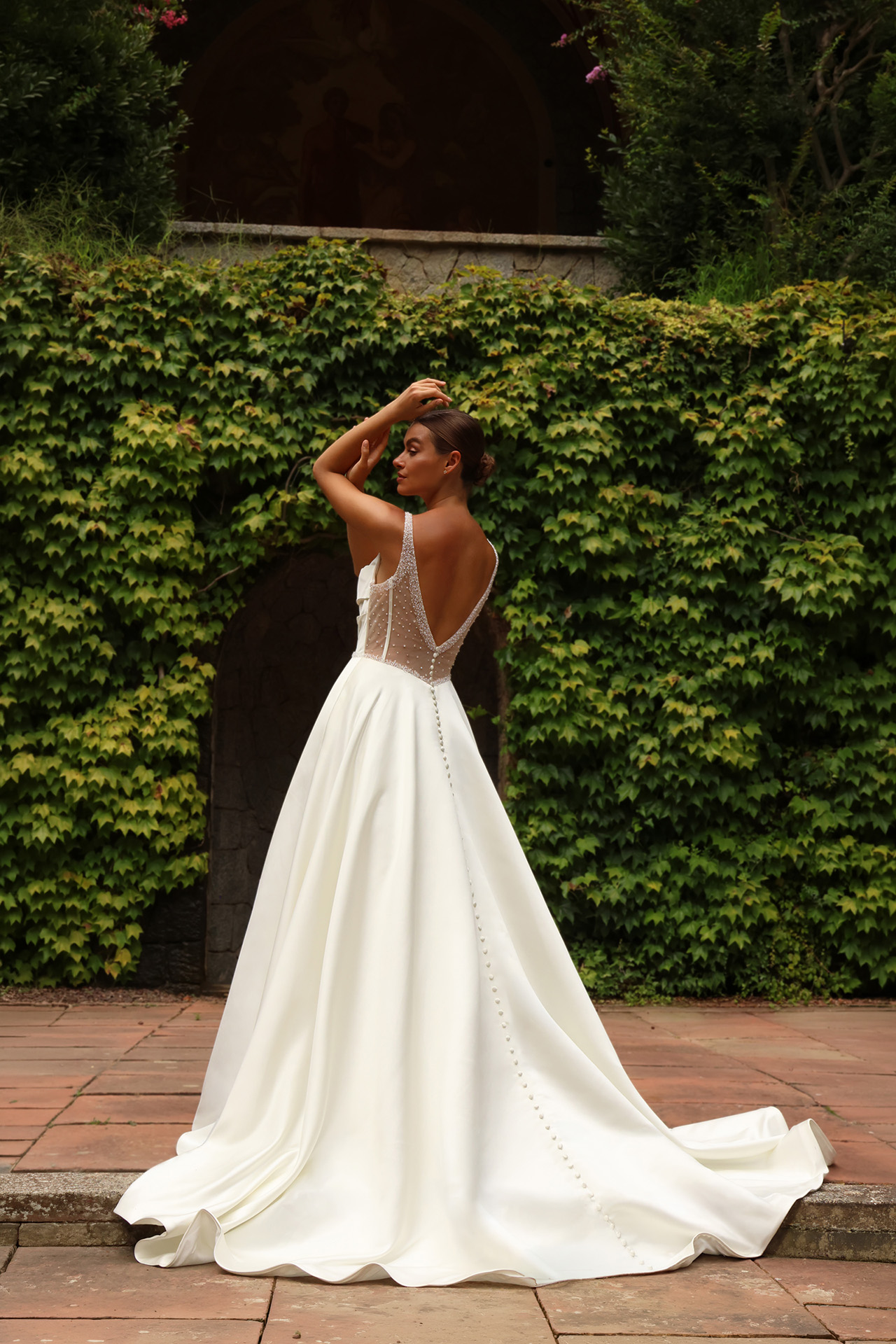 Vue arrière de la robe de mariée Apolline en crêpe fluide avec dos illusion et longue traîne.
