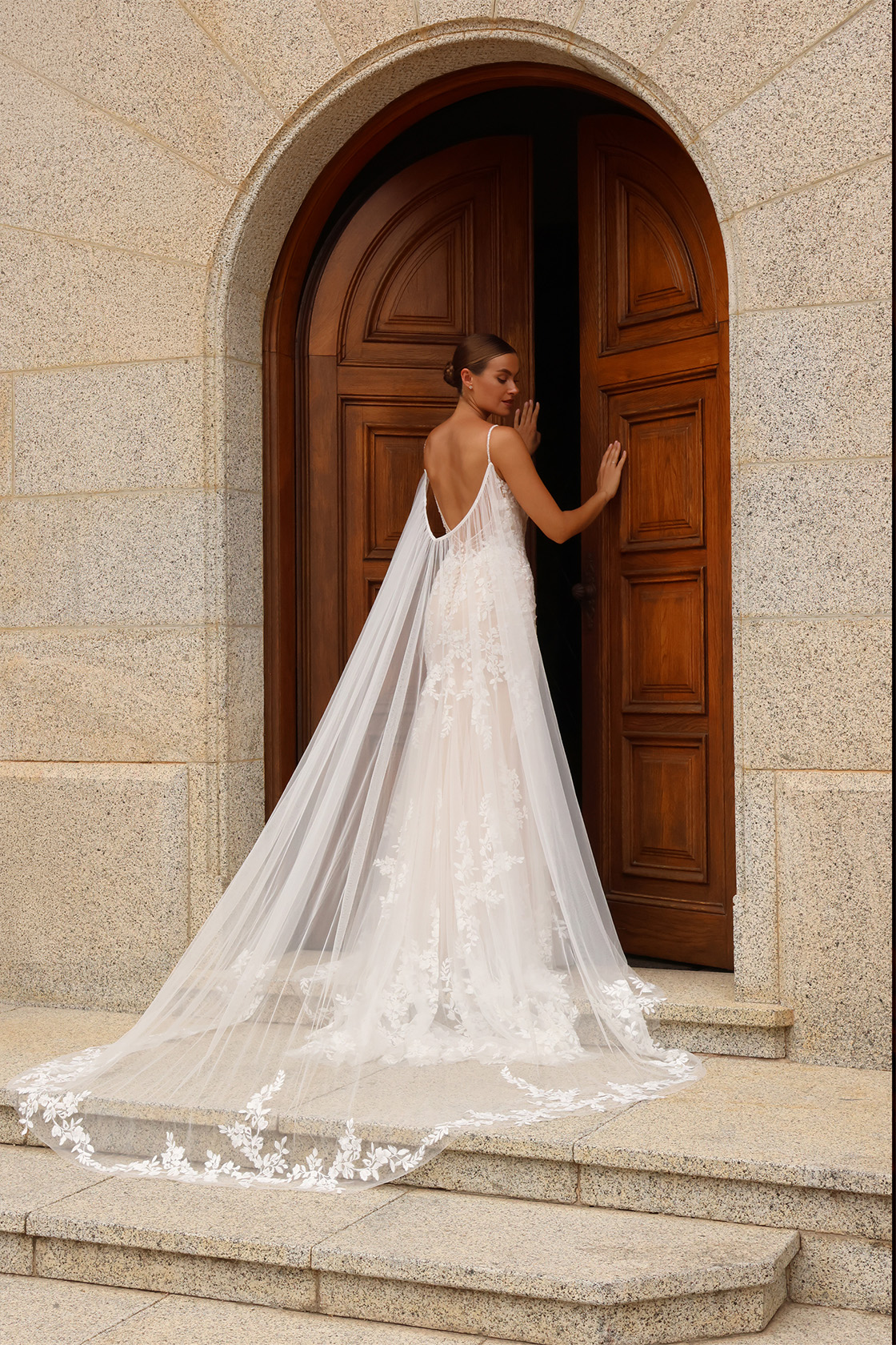 Vue dos de la robe de mariée Garance avec dos nu profond et longue cape amovible bordée de dentelle florale.