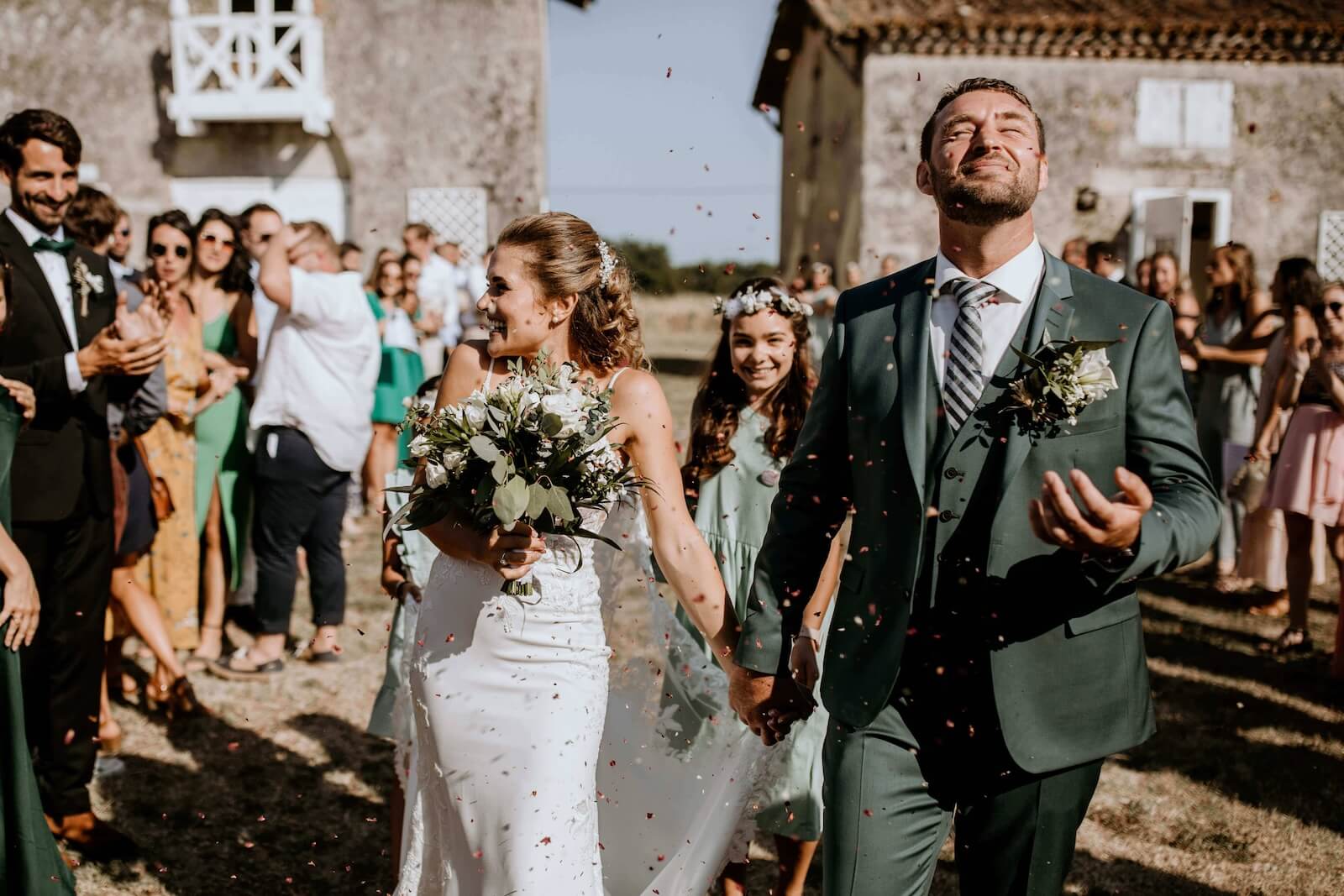Sylvie et Julien marchent main dans la main devant leurs invités, la mariée tenant son bouquet.